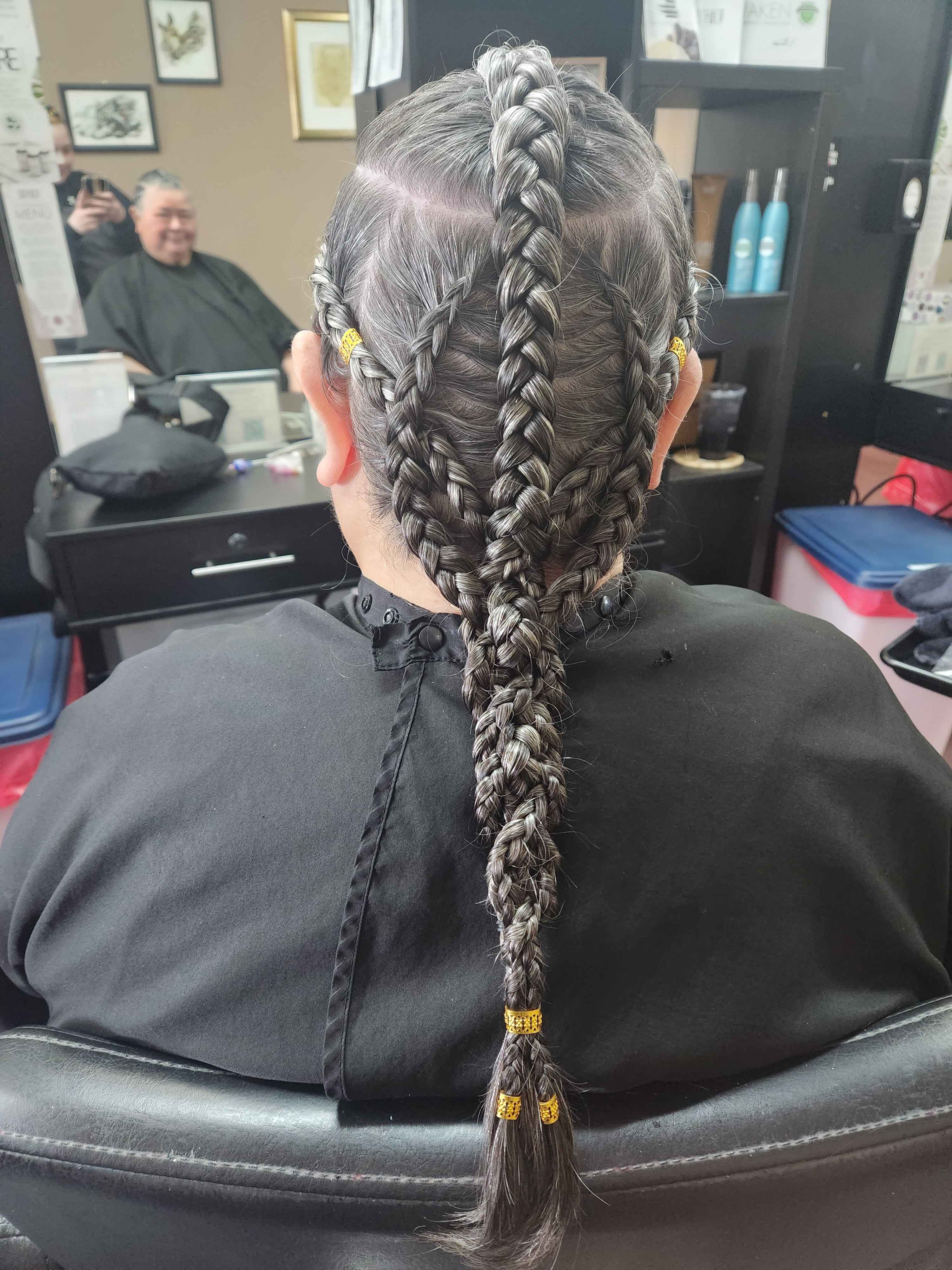 a client with naturally grey hair that is braided back into an intricate log braid, consisting of five individual dutch braids woven together with golden metal cuff accents