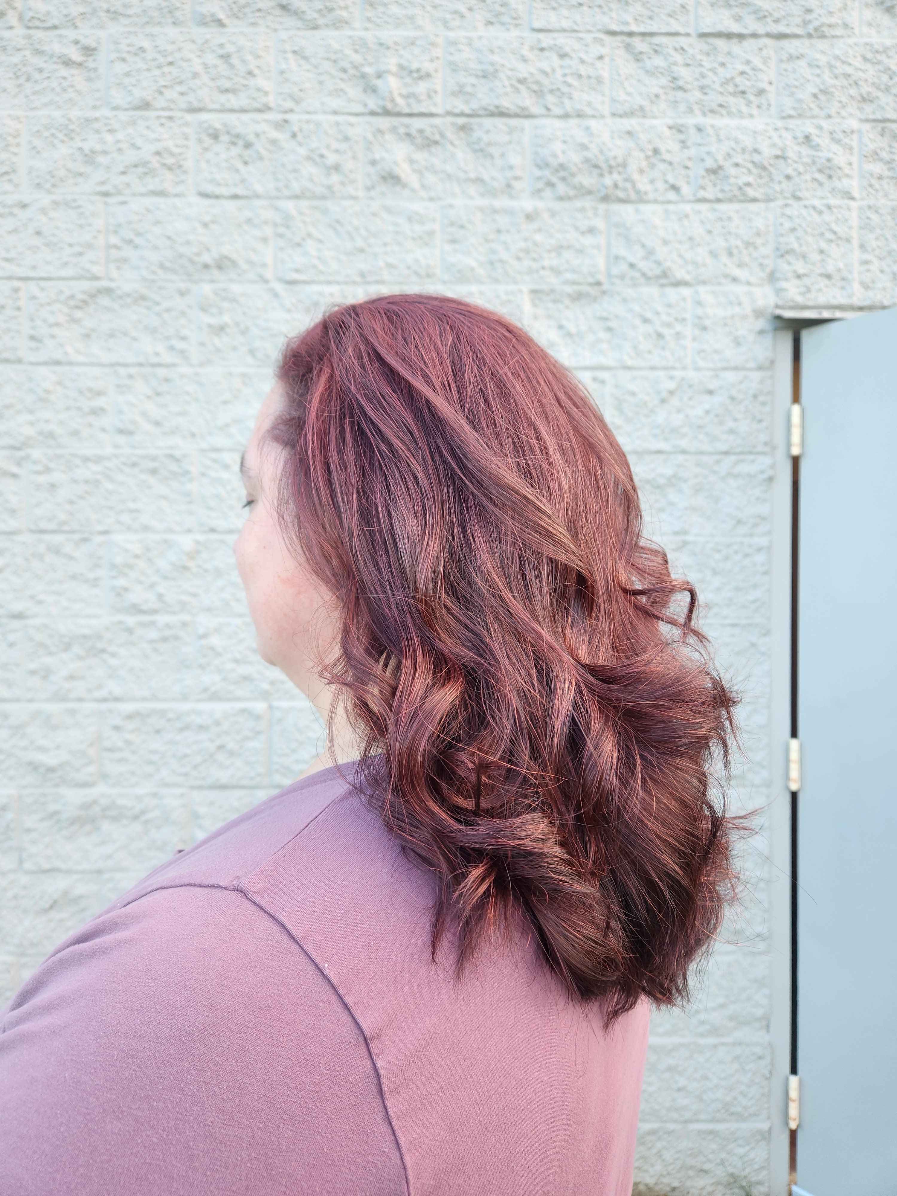 same client with shoulder-length multi-demetional maroon red hair. styled with curls.